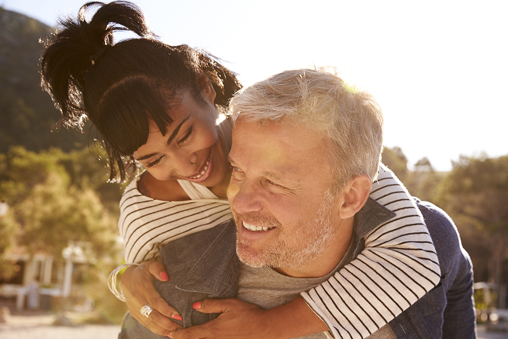 Man carrying happy woman on his back